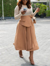 Woman in a high-waist pleated skirt walking stylishly in an outdoor setting, perfect for fall and winter fashion.