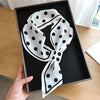 Small long strip silky scarf with black polka dots elegantly displayed in a gift box. Stylish fashion accessory for women.