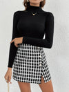 Elegant plaid asymmetrical skirt with button detail, styled with a black turtleneck for a chic fall look.